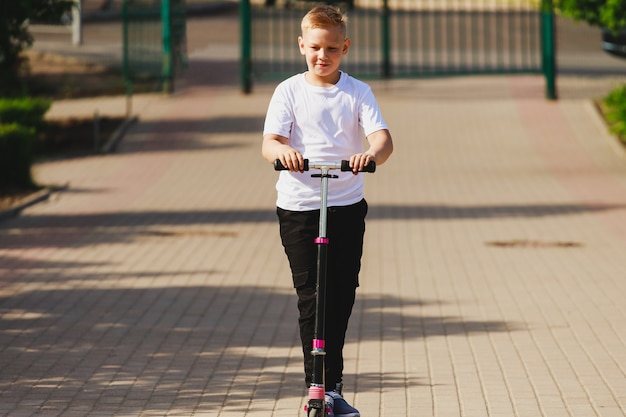 A young boy rides a scooter in the park in the summer. High quality photo