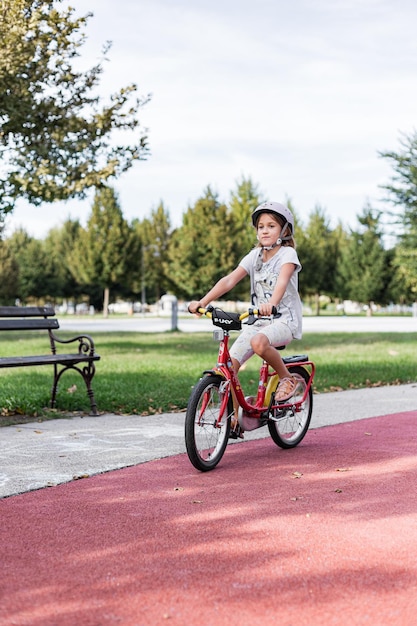 A young boy riding on his bicycle in summer with a helmet on