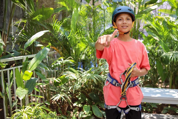 Young boy in safety equipment giving thumb up ready to climbing in adventure