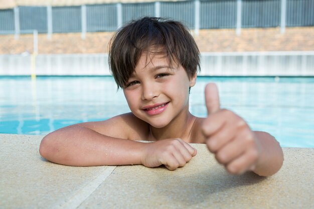 Молодой мальчик показывает палец вверх у бассейна