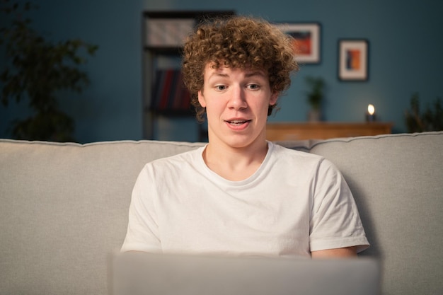 A young boy sits in the living room in the evening and uses a
laptop