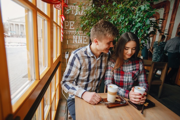 Photo young boy sitting in a cafe and drinking coffee with his girlfriend