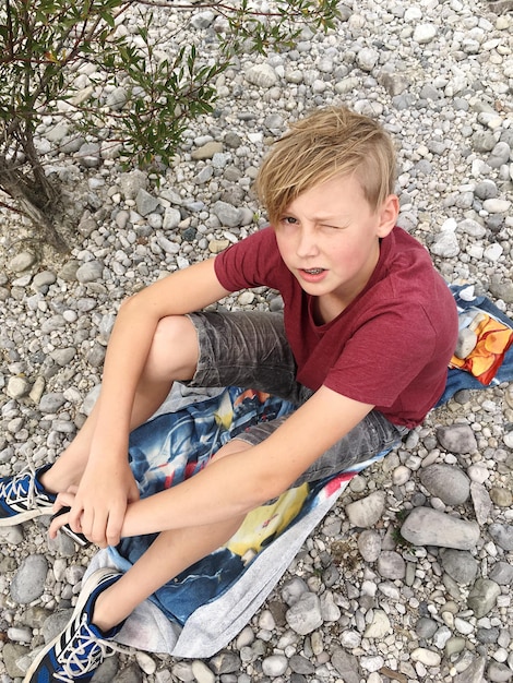 Photo young boy sitting on rocks