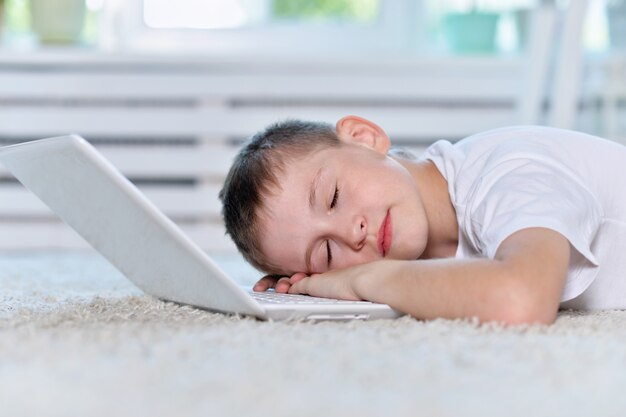 Young boy sleeping near and  laptop computer