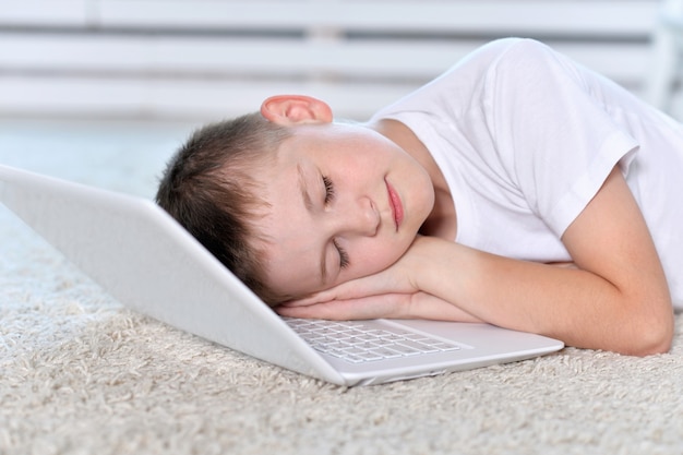 Young boy sleeping near and  laptop computer