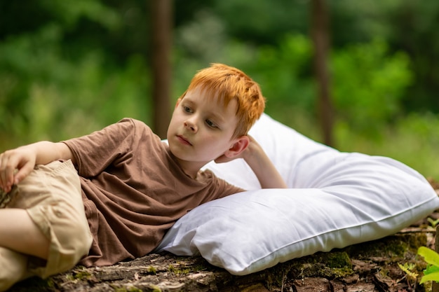 A young boy sleeps on a pillow in the woods