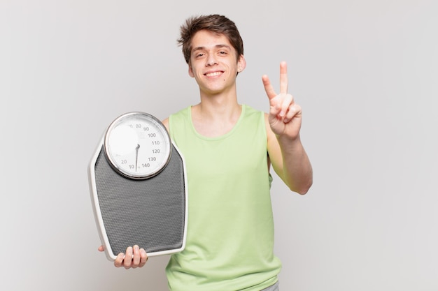 young boy smiling and looking happy, carefree and positive, gesturing victory or peace with one hand scale concept