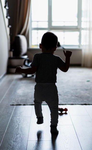 Мальчик стоит на полированном деревянном полу Маленький мальчик стоит на твердом деревянном полу