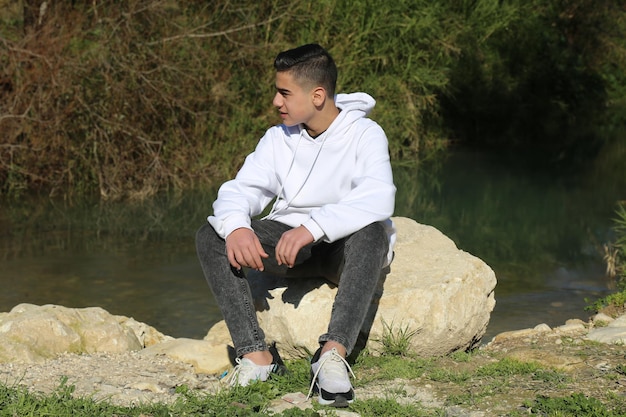 A young boy stands amidst the lush greenery of the forest