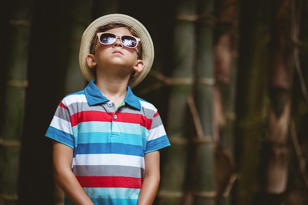 Young boy in sunglasses standing in forest