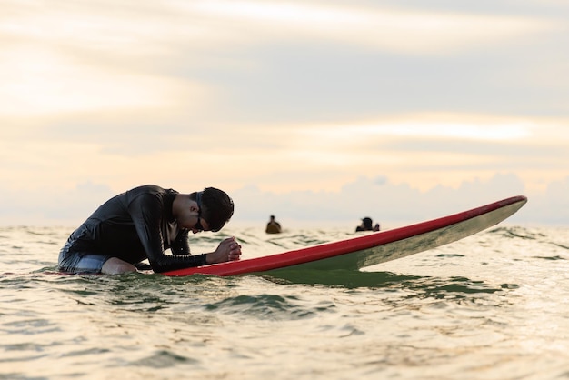 Photo young boy teenager surfboarder bows his head in exhaustion tired and disappointment during learning and practicing surfing