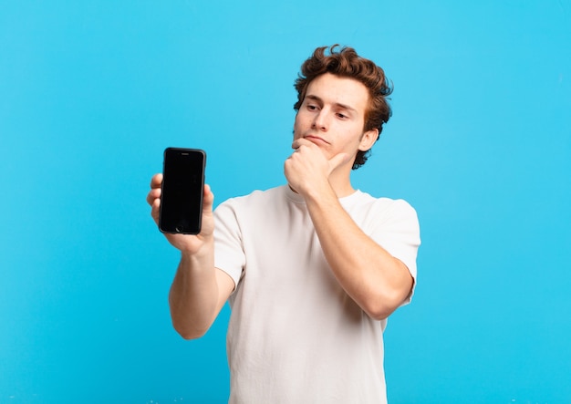 Young boy thinking, feeling doubtful and confused, with different options, wondering which decision to make. telephone screen concept