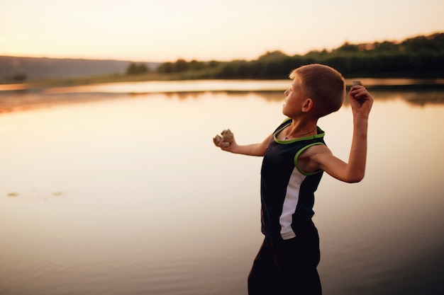 Foto ragazzo giovane che lancia sassi in un lago