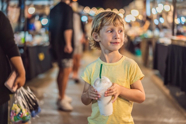 Giovane turista del ragazzo sul mercato alimentare asiatico di walking street