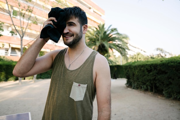 Young boy training outdoors in a tank top wiping off sweat with a black towel