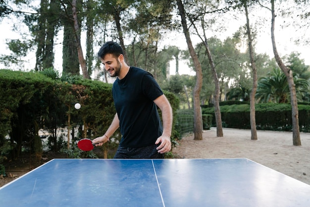 Young boy training ping pong outdoors in a tank top