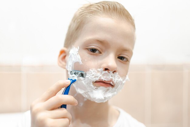 A young boy tries to shave his face for the first time Kid with shaving foam