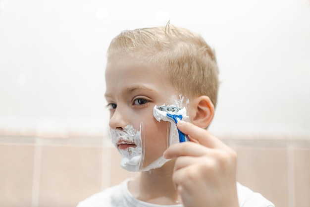 A young boy tries to shave his face for the first time Kid with shaving foam