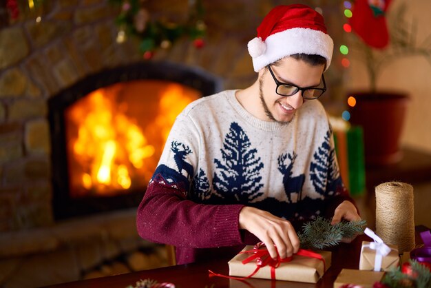 クリスマスプレゼントにリボンを結ぶ少年。新年の気分、ぼやけた光。バックグラウンドで炉床火災