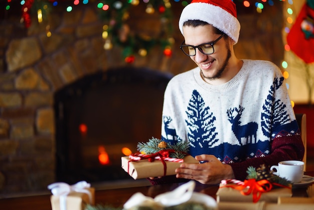 Young boy Tying Ribbon on Christmas Present New Year's mood blurred lights hearth fire in background