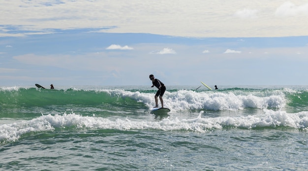 Foto il giovane ragazzo che indossa gli occhialini da nuoto sta stabile su una tavola morbida mentre pratica il surf nella classe per principianti