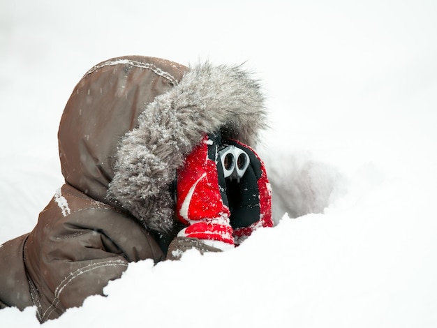 Photo young boy wearing winter jacket with furry hood and red gloves looking through binocular