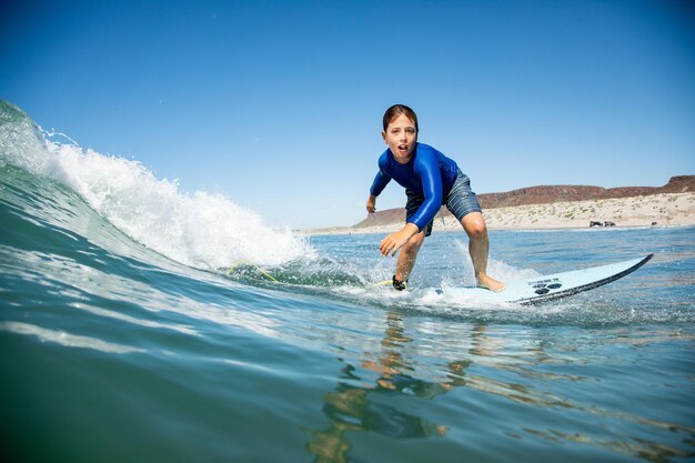 Photo young boy in a wetsuit surfing in the ocean