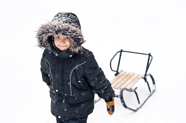 Giovane ragazzo in abito invernale tirando le slitte