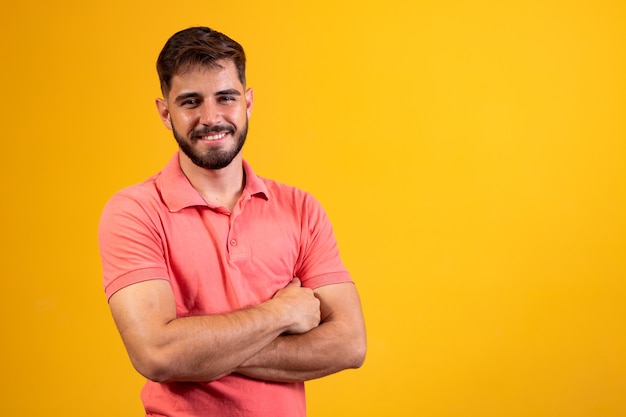 Young boy with arms crossed smiling on yellow background with free space