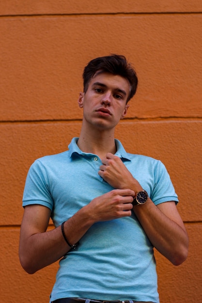 Young boy with blue polo shirt waiting on orange background on the street