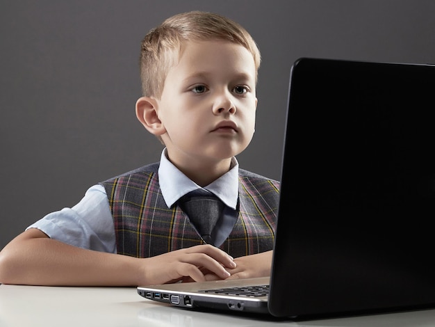 Young boy with computer child looking in notebook