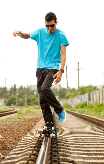 Young boy with skateboard at railway.