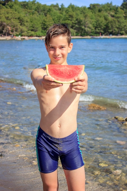 Фото Маленький мальчик с кусочком арбуза на пляже возле моря