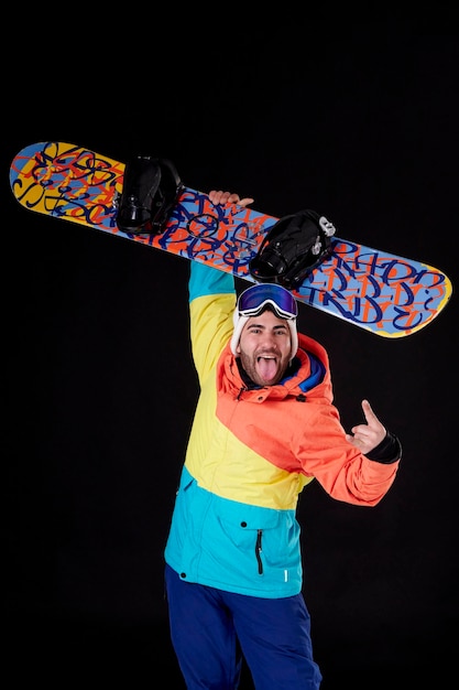Young boy with snowboard sticking his tongue out at the camera