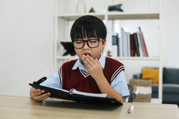 Photo young boy yawning as he does his homework