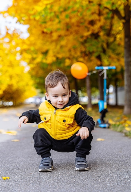 Foto ragazzo in giacca gialla che gioca con la palla un giovane ragazzo allegro che indossa una giacca gialla gioiosamente gioca con la sua palla