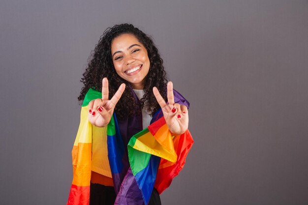 Photo young brazilian black woman sign of peace and love militancy with lgbt flag diversity