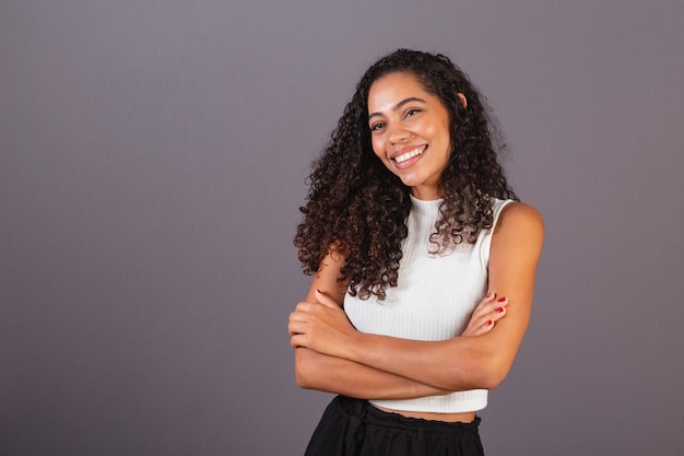 Young Brazilian black woman with arms crossed smiling