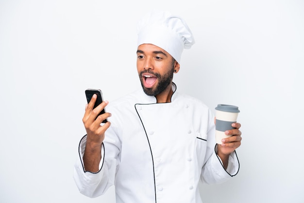 奪うためにコーヒーと携帯電話を保持している白い背景で隔離の若いブラジル人シェフの男