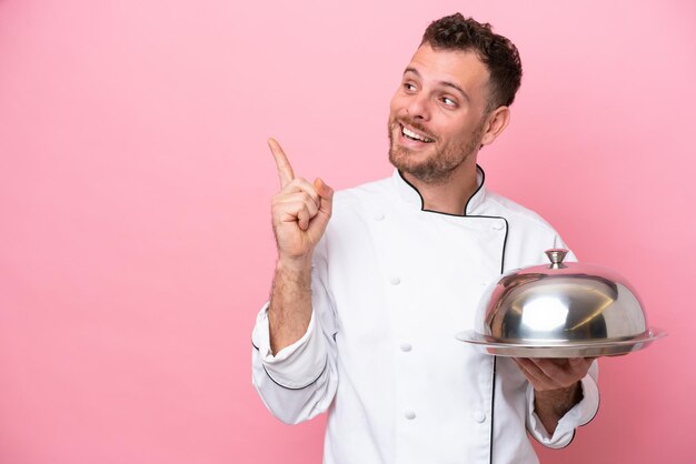 Young Brazilian chef with tray isolated on pink background intending to realizes the solution while lifting a finger up