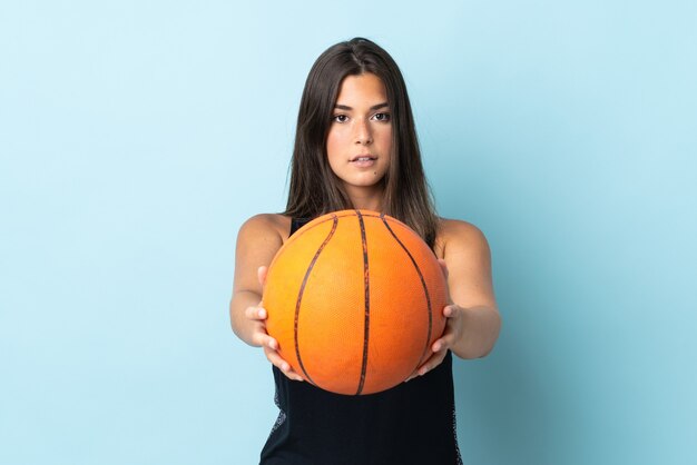 Young brazilian girl isolated on blue wall playing basketball