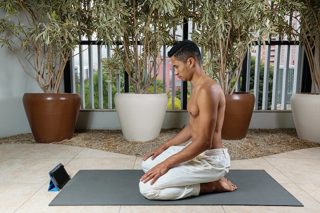 Молодой бразильский мужчина готовится начать занятия йогой онлайн.