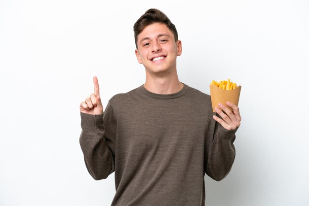 Young Brazilian man holding fried chips isolated on white background pointing up a great idea