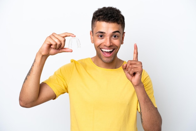 Young Brazilian man holding invisible braces isolated on white background pointing up a great idea