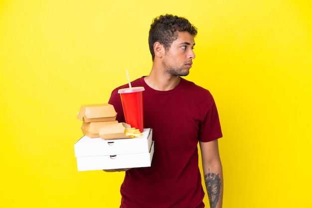 Il giovane brasiliano che tiene le pizze e gli hamburger ha isolato il fondo che guarda al lato