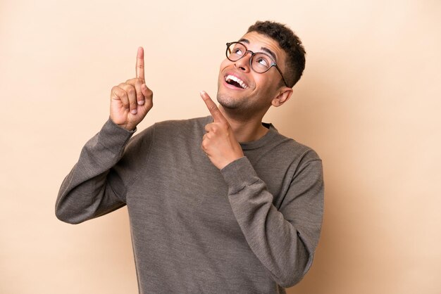 Young Brazilian man isolated on beige background pointing with the index finger a great idea