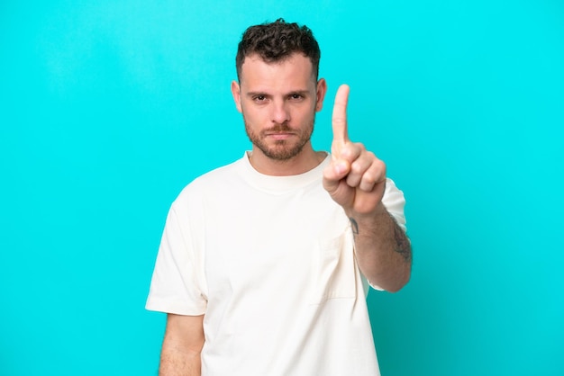 Young Brazilian man isolated on blue background counting one with serious expression