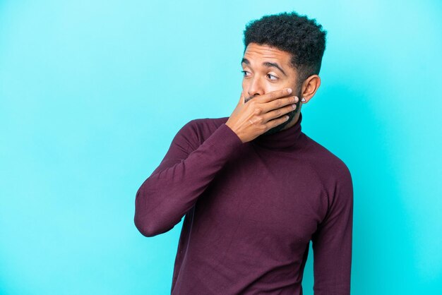 Young Brazilian man isolated on blue background doing surprise gesture while looking to the side