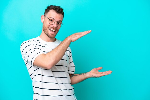 Young brazilian man isolated on blue background holding copyspace to insert an ad