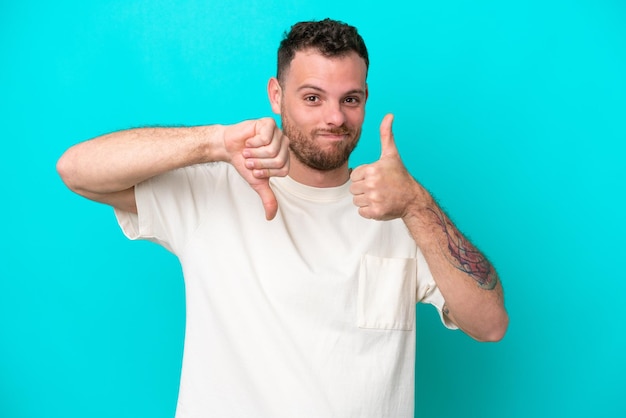 Young Brazilian man isolated on blue background making goodbad sign Undecided between yes or not